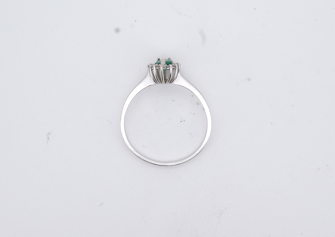 A modern white metal(stamped 14k), emerald and diamond set pear shaped cluster ring, size R, gross weight 1.3 grams.